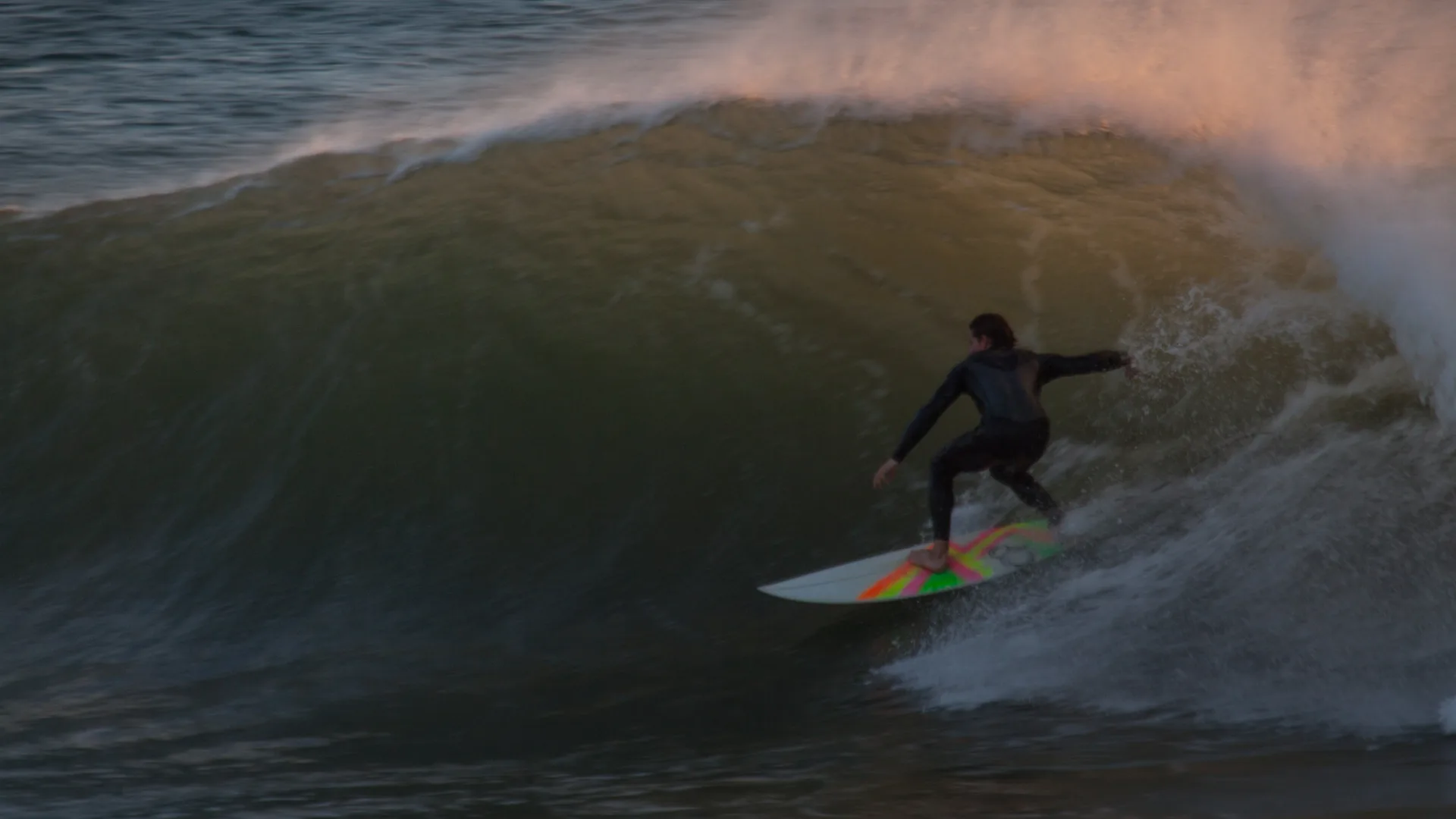 Surfeur sur une vague au crépuscule à Anchor Point, Taghazout, Maroc