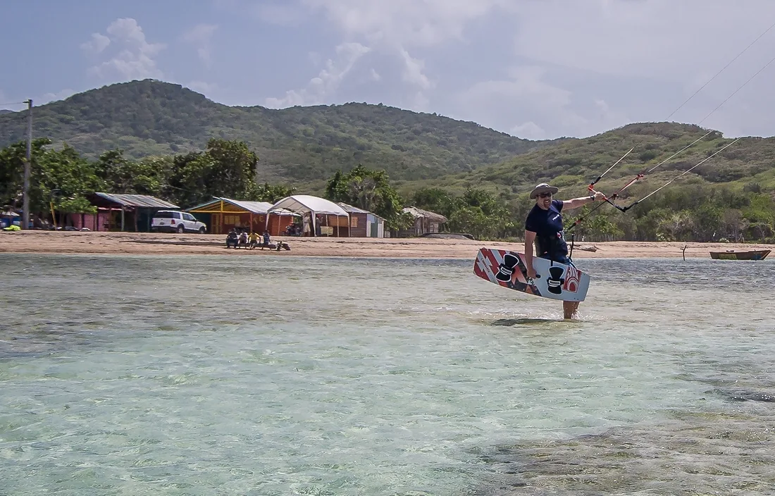 Kitesurfeur rejoignant la plage devant le village de Buen Hombre, collines vertes derrière