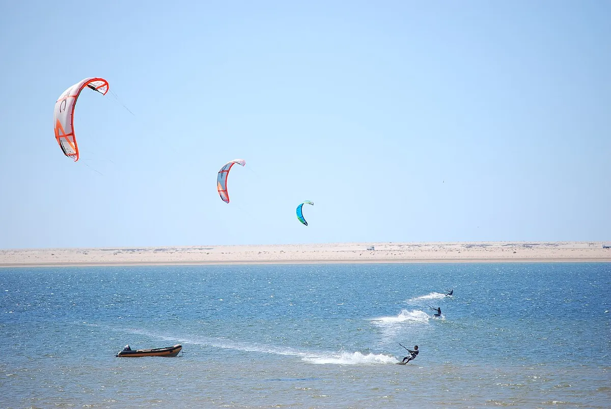 Kitesurfeurs sur une eau bleue à Dakhla, une bande de sable en arrière-plan
