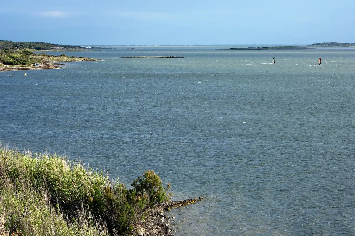 L'étang de Leucate vu depuis la rive, avec deux windsurfeurs au loin