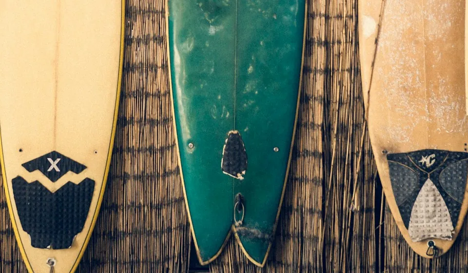 Planche verte à queue en swallow tail, échancrée en V, entre d'autres planches appuyées contre un mur