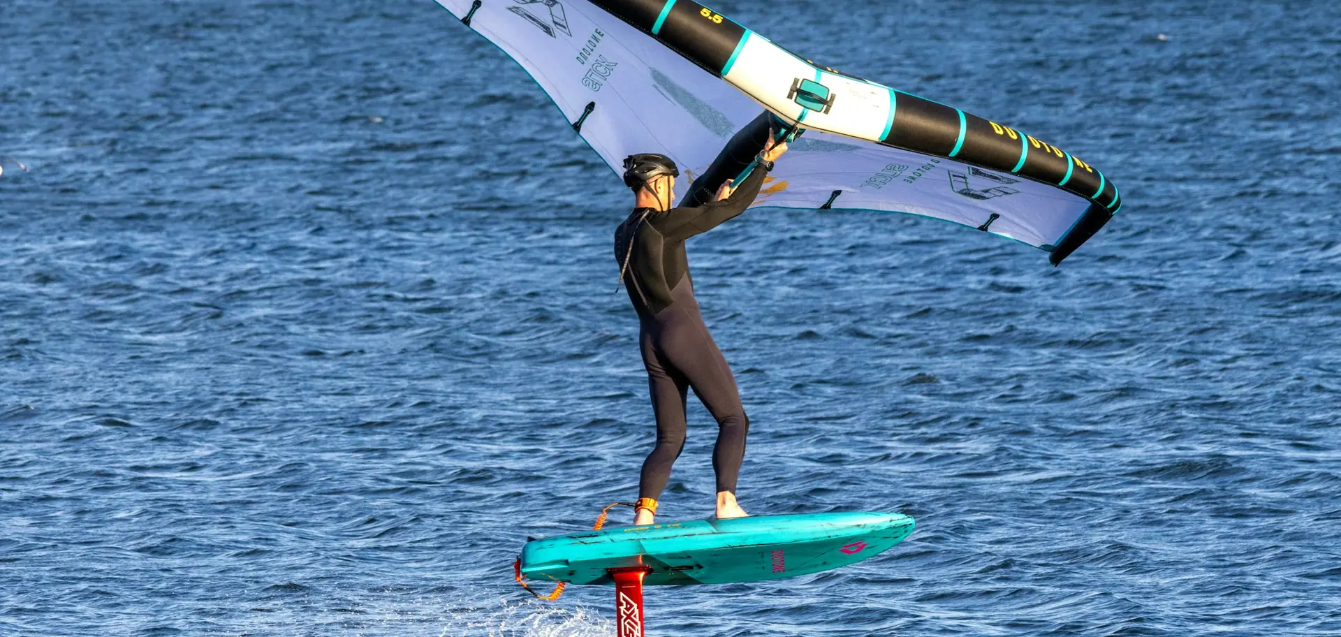 Surfeur sur un foil au-dessus de l'eau, vagues en arrière-plan