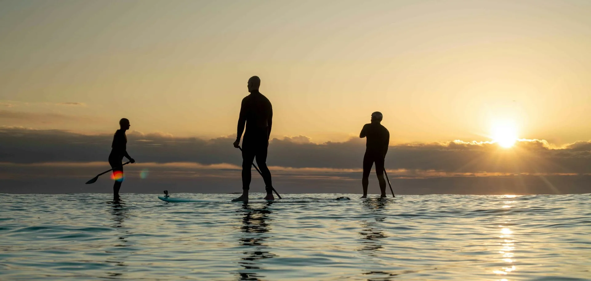 Groupe de pratiquants de paddle SUP au coucher de soleil