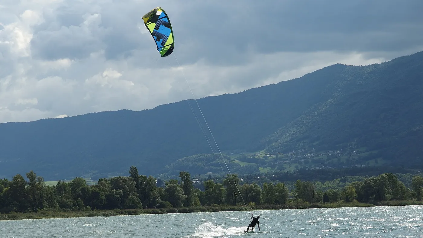 Kitesurfeur sur le lac du Bourget, aile dans le ciel et montagnes en arrière-plan