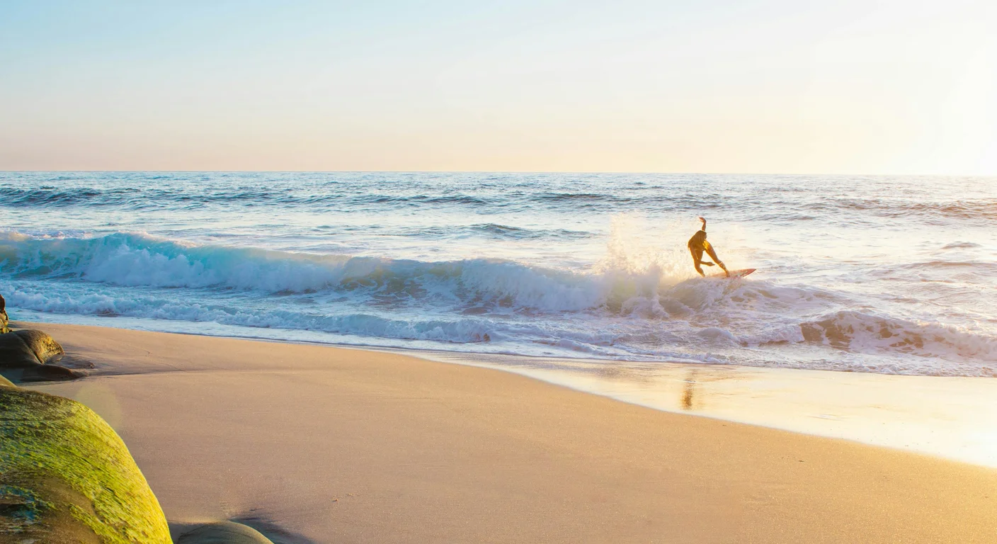 Matériel de surf posé sur la plage : planche et combinaison néoprène