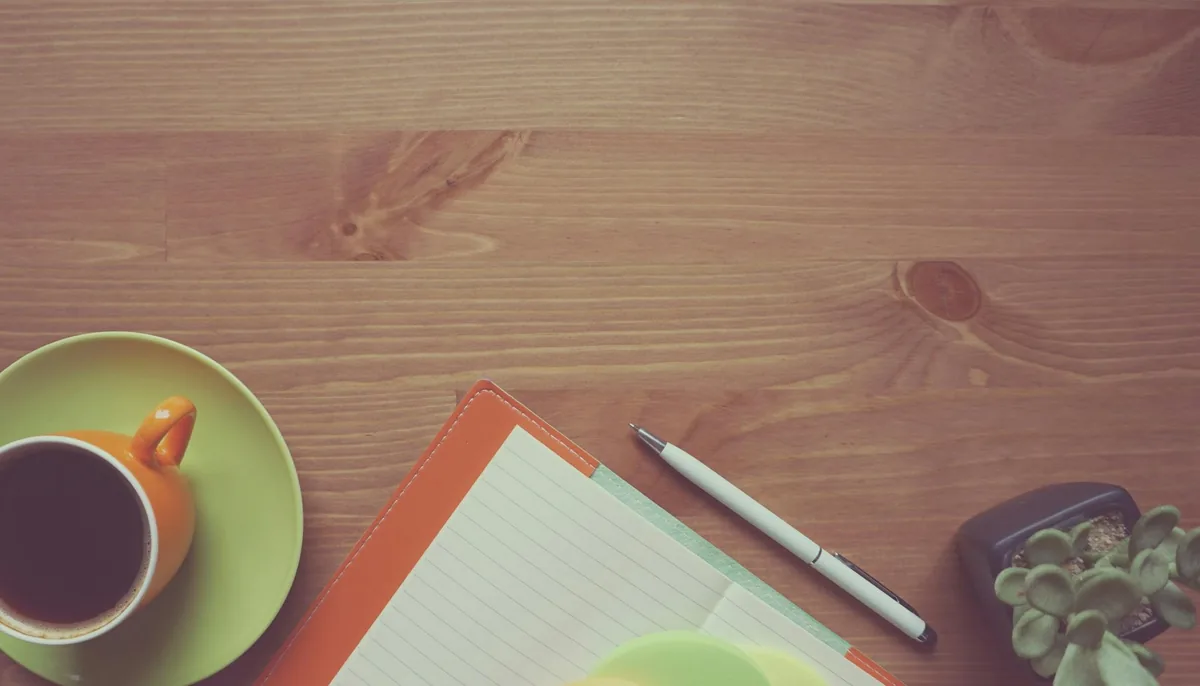 Carnet de notes, stylo et tasse de café sur une table en bois