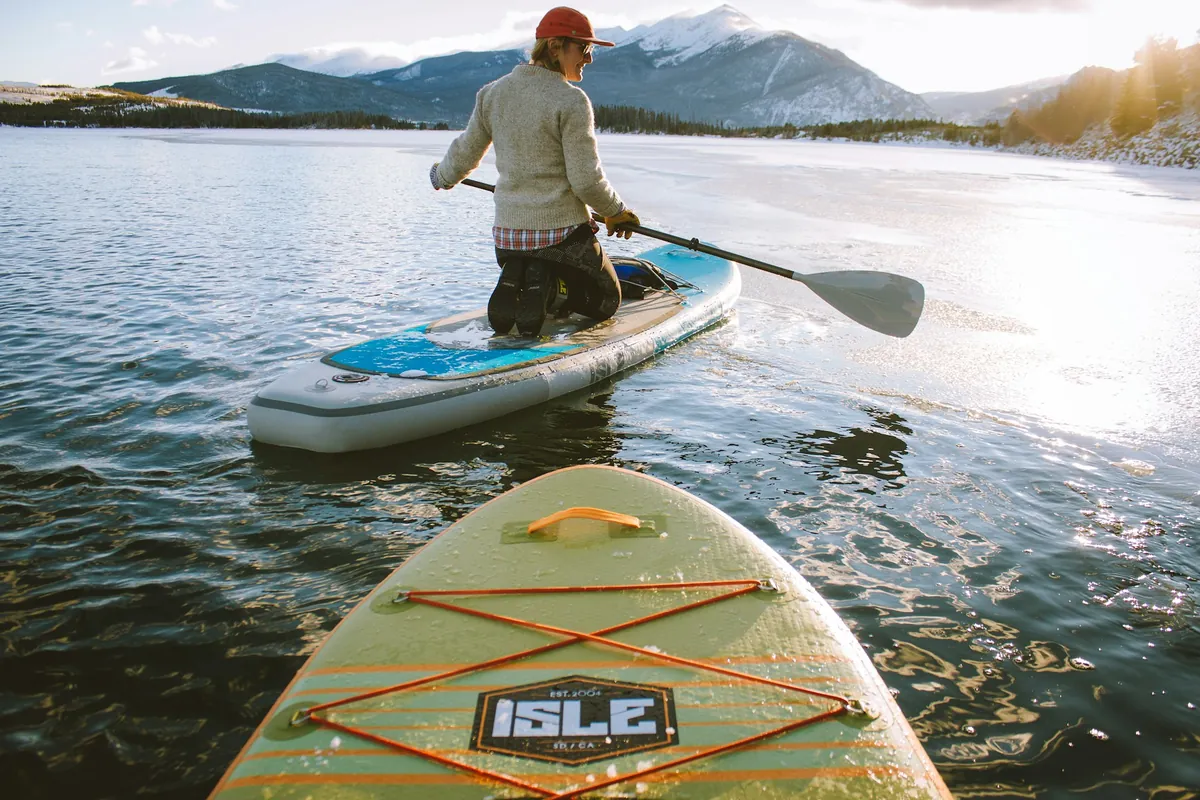 Pagayeur à genoux sur un paddle, sur un lac de montagne