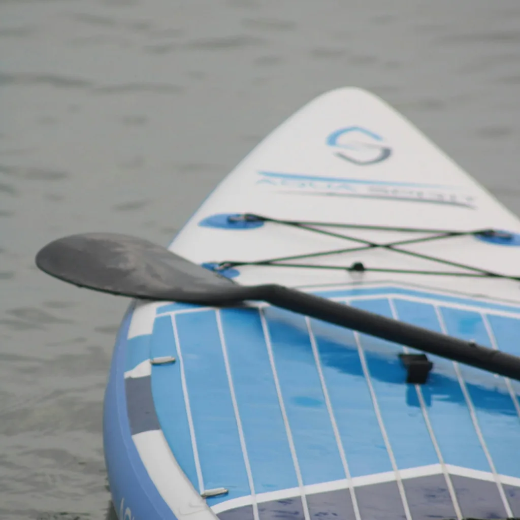 Gros plan sur l'avant d'une planche de SUP, pagaie posée en travers