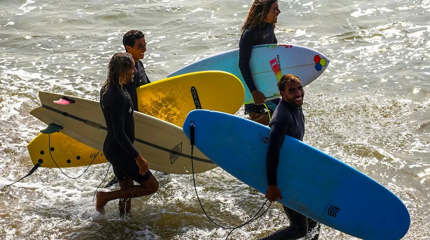 Groupe de surfeurs sortant de l'eau avec leurs planches sous le bras