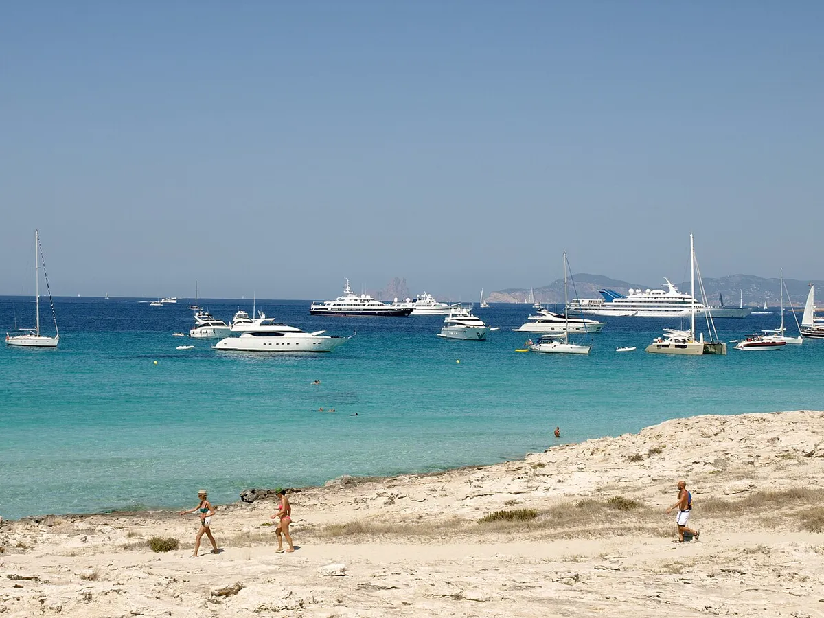 Yachts et voiliers au mouillage dans une eau turquoise, au large du rivage rocheux clair de Ses Illetes, à Formentera