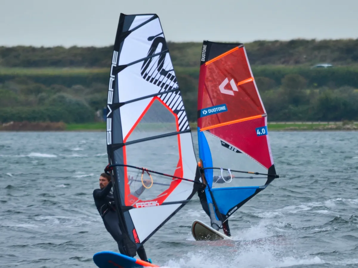 Deux windsurfeurs naviguant à proximité l'un de l'autre sur une eau agitée