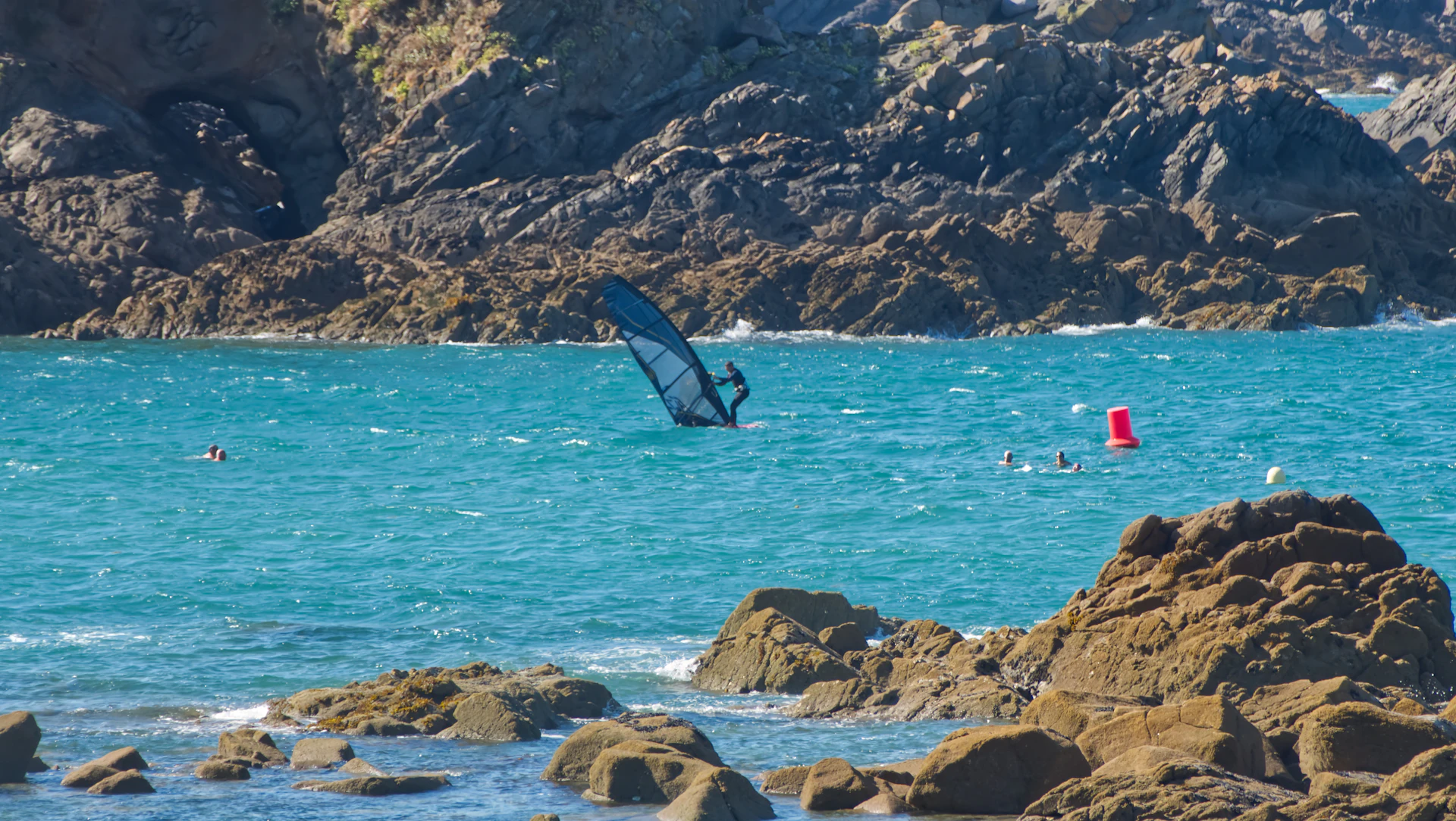 Planche à voile près d'une côte rocheuse