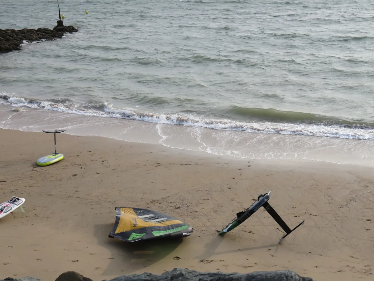 Aile à plat sur le sable et planche à foil posée à côté, plage de La Rochelle